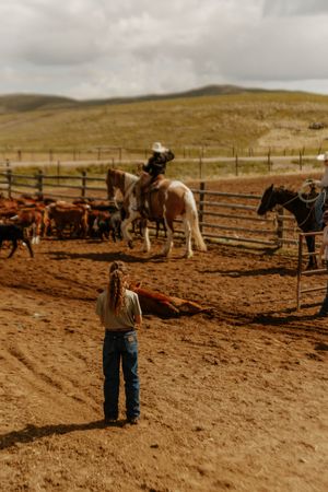 A young girl watching the older generations work and  tend to cattle on family land in Bancroft Idaho.