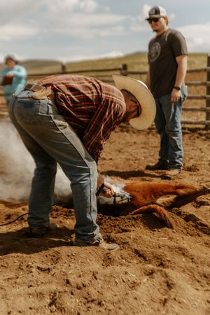 Western Cattle Workers perform maintenance on a dirt ranch area under blue skies.