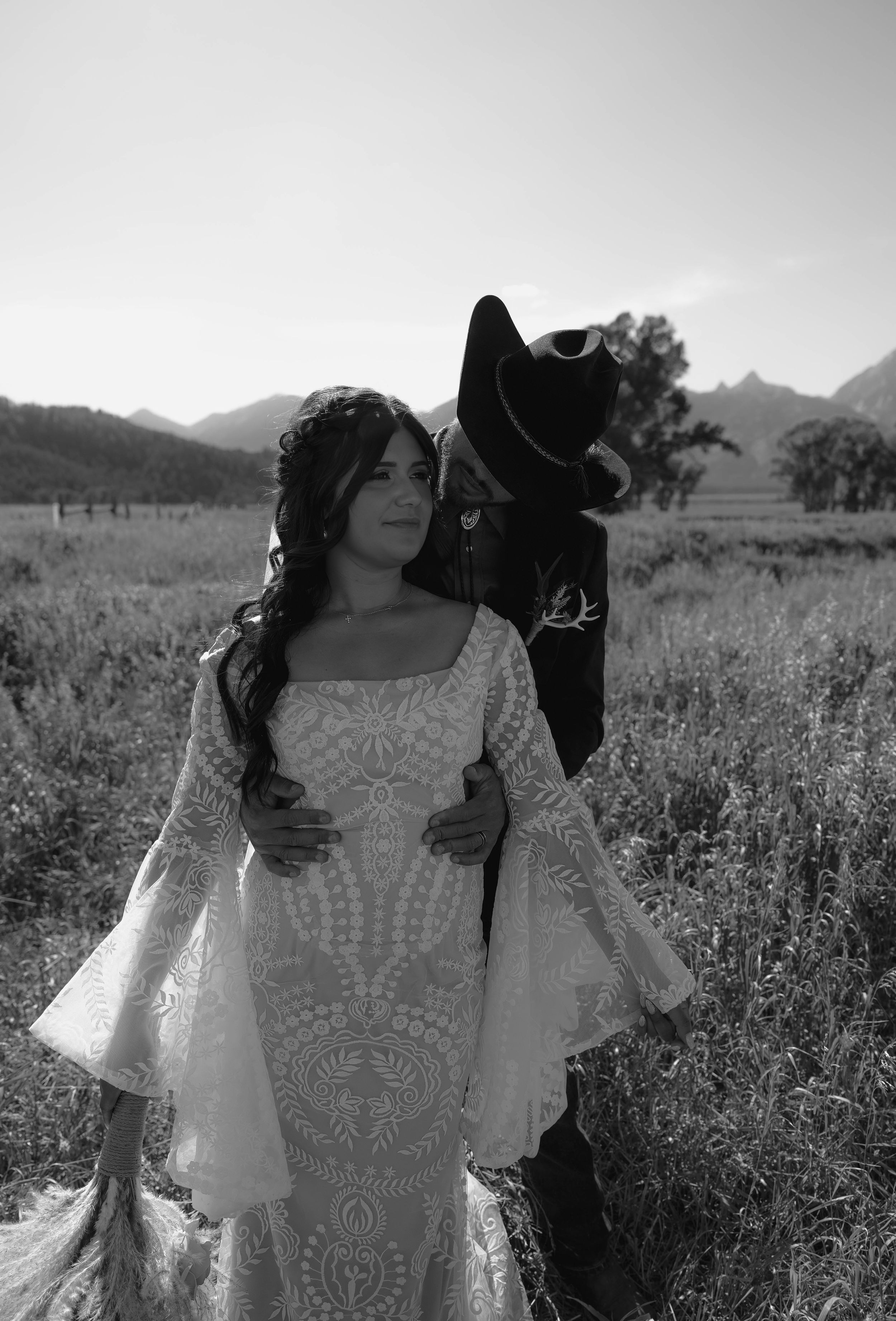 A black and white portrait of a western couple in wedding attire against the Grand Teton mountains.
