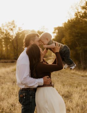 A loving western family moment captured at sunset in a golden field.
