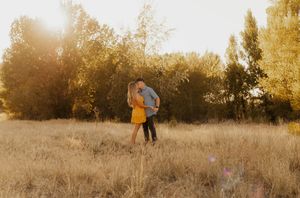A sunset scene with golden light filtering through trees in a natural landscape. A Casual western couple.