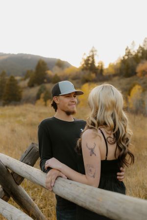 Couple sitting on a fallen log in a golden mountain meadow at sunset. Western couple