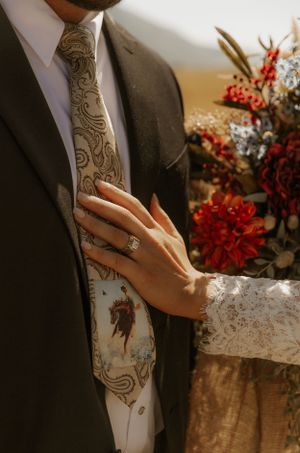 Close-up of hands showing western wedding rings and formal attire with lace details.