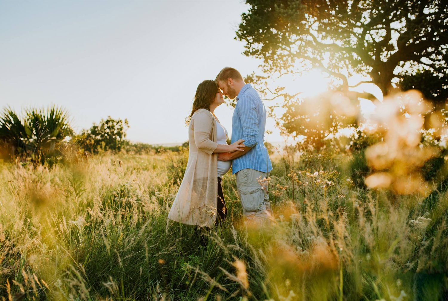 Maternity couple standing together in an open field, celebrating pregnancy and connection