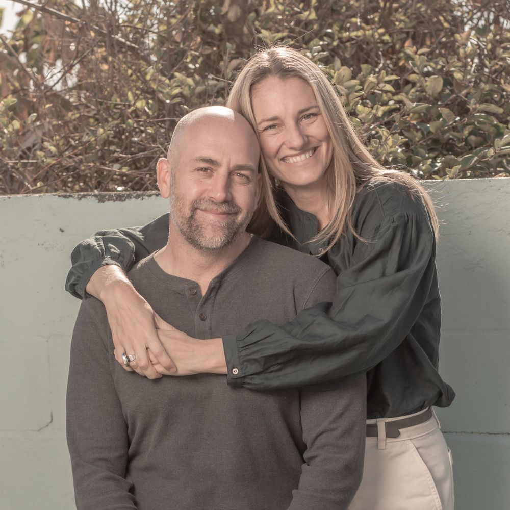 A couple embraces and smiles warmly while posing together outdoors. Family portrait photography.