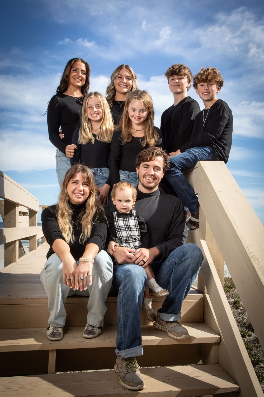 Family group portrait on outdoor stairs against blue sky background. Family portrait photography.