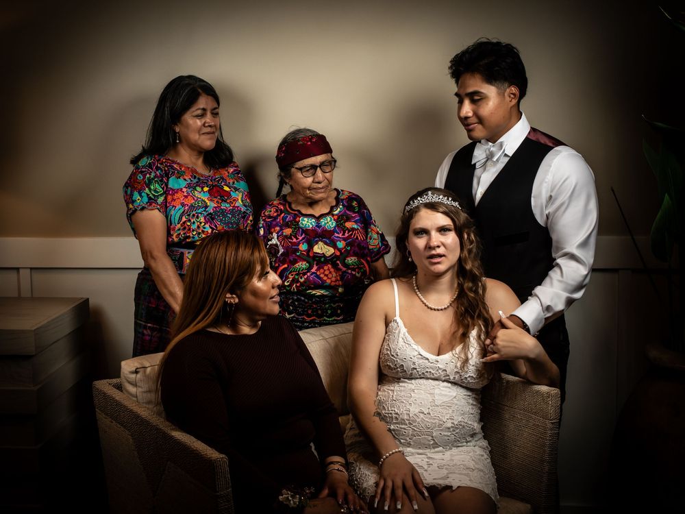 A tender moment captured during a wedding preparation as people share laughter and conversation in a dimly lit room.