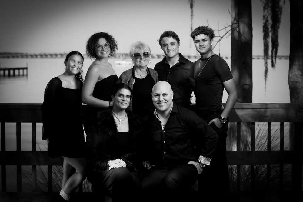 Black and white family portrait of group seated and standing on porch. Family portrait photography.