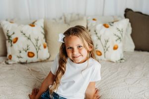 White throw pillows with orange pumpkin pattern decorate a cozy bed with textured bedding.