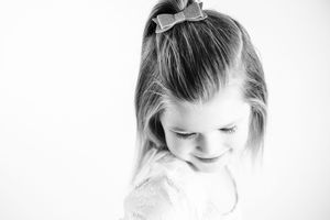 Black and white artistic portrait of a child looking down with a gentle smile in a minimalist style.