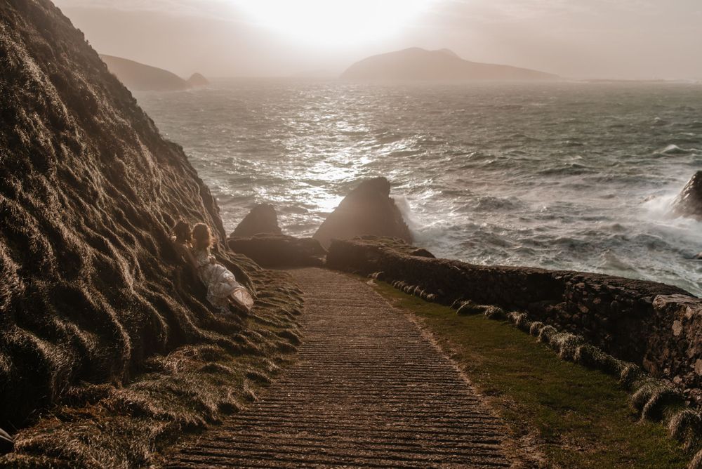 Misty coastal path winding along dramatic seaside cliffs at sunset.