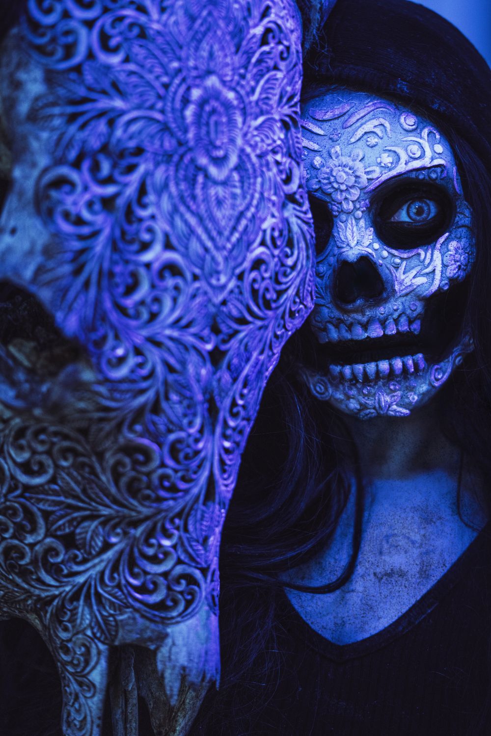 Day of the Dead inspired makeup featuring skull face paint and dramatic blue lighting effects.