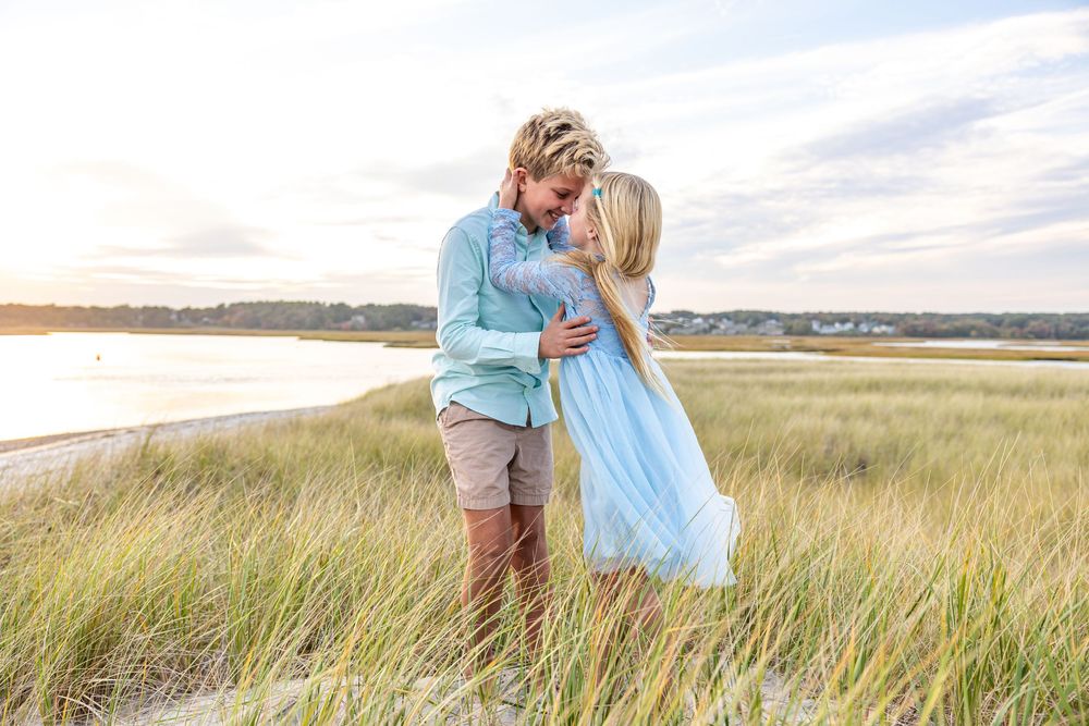 A couple embraces lovingly in a sun-drenched meadow of tall grass during golden hour.