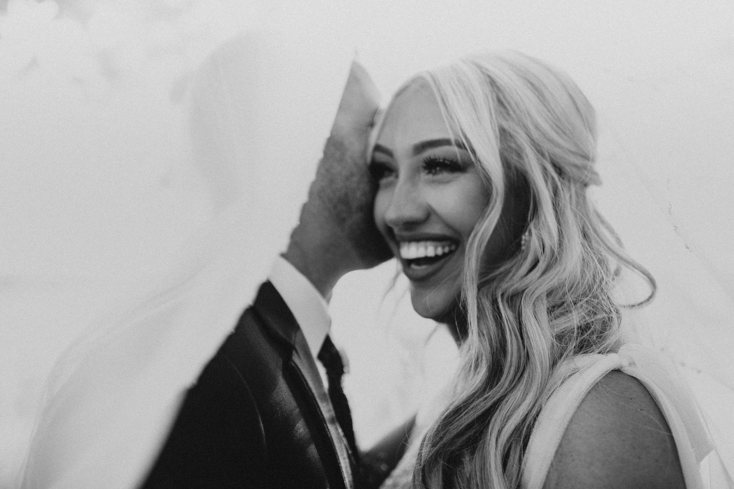 Black and white candid wedding photo capturing pure joy and laughter between newlyweds.