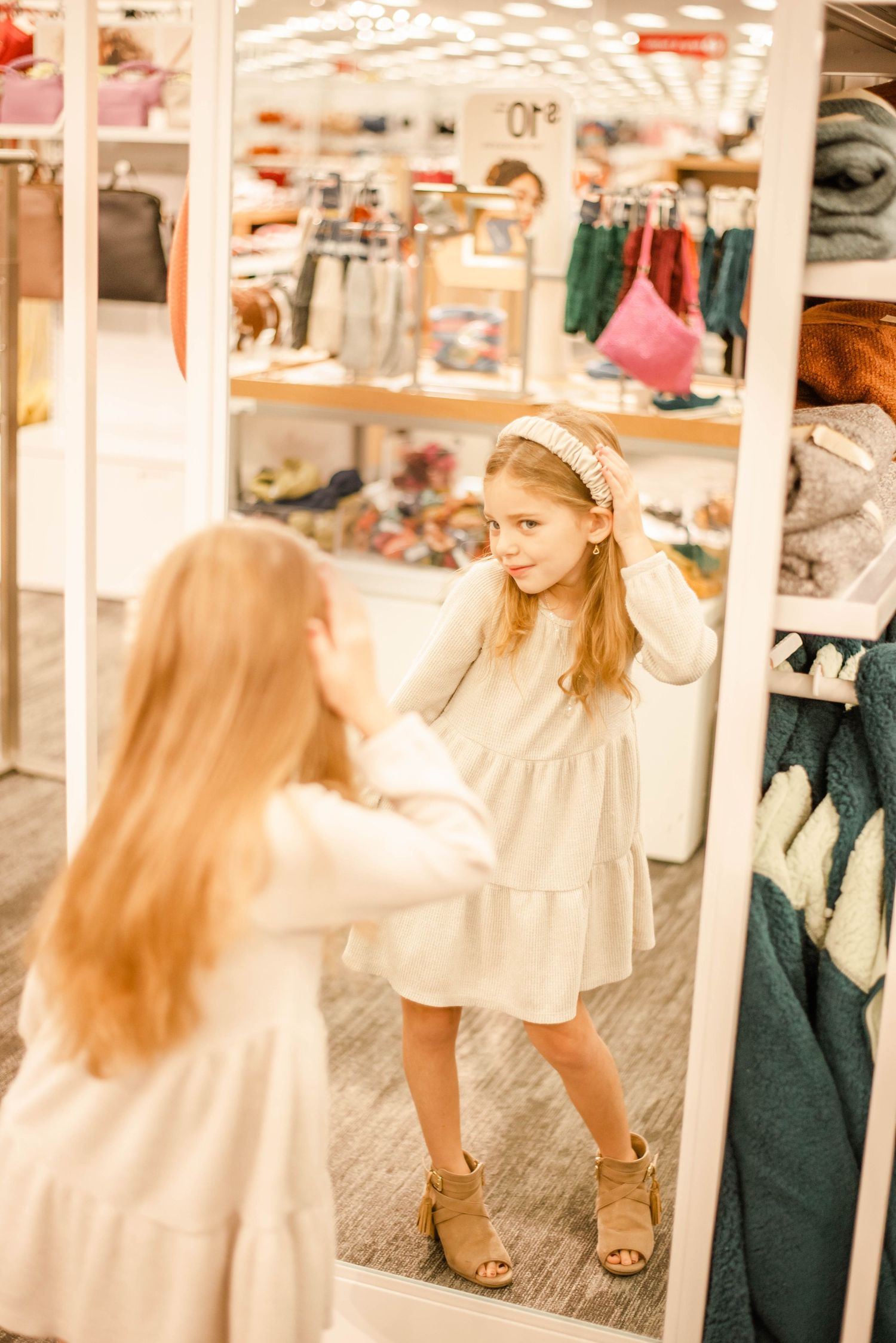 Young person in a white dress browsing toy store shelves in a playful sequence of motions.