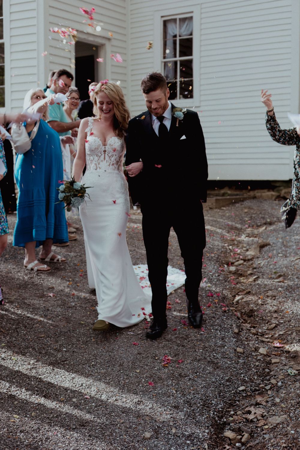A couple exits their wedding ceremony while guests toss pink flower petals.