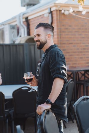 People enjoying drinks and conversation on an outdoor patio with brick walls and string lights in the background.