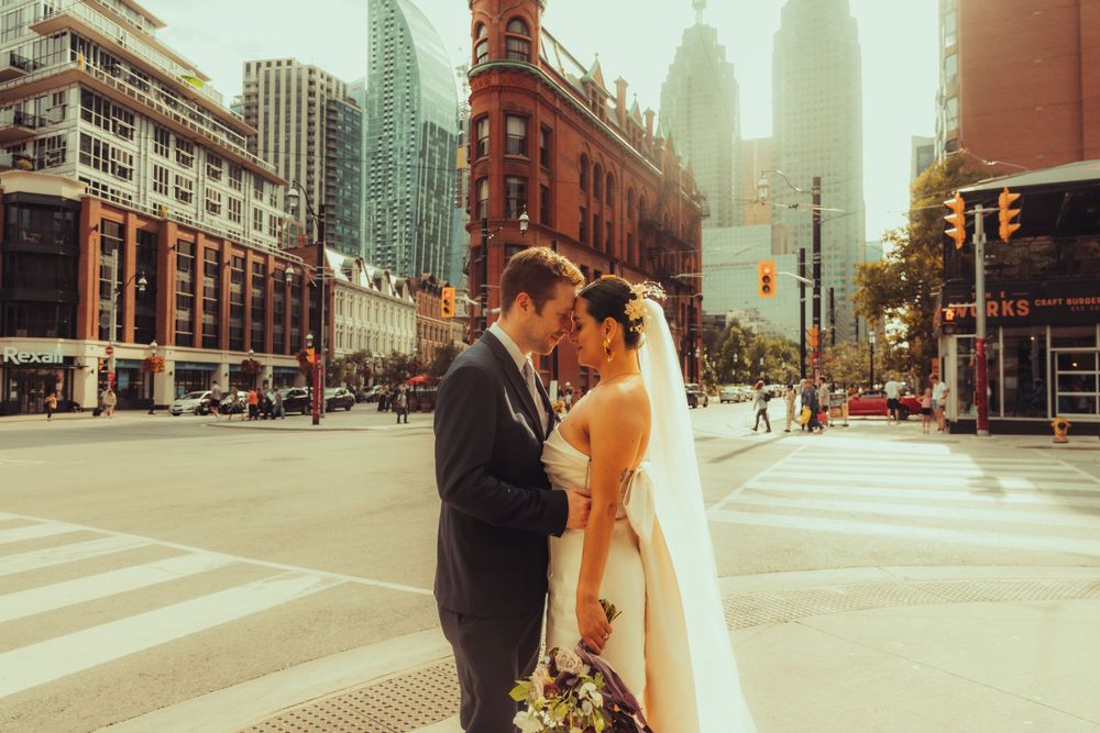Golden hour photo of a bride and groom hugging each other front Gooderham Building
