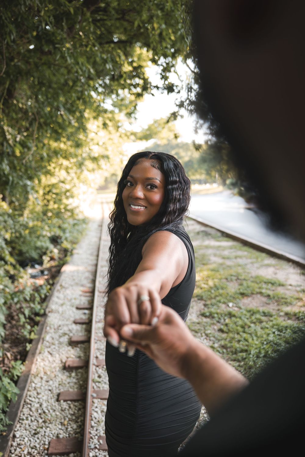 Engagement photo on train tracks with joyful expression.