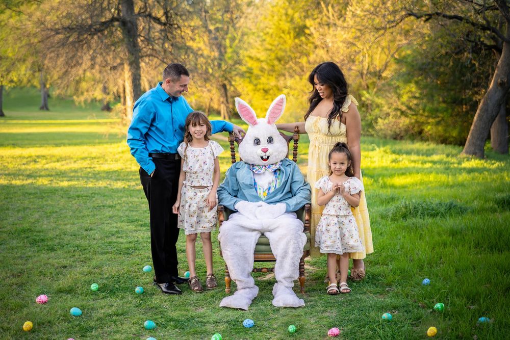 A family poses in a beautiful green field with the Easter Bunny in an antique chair.