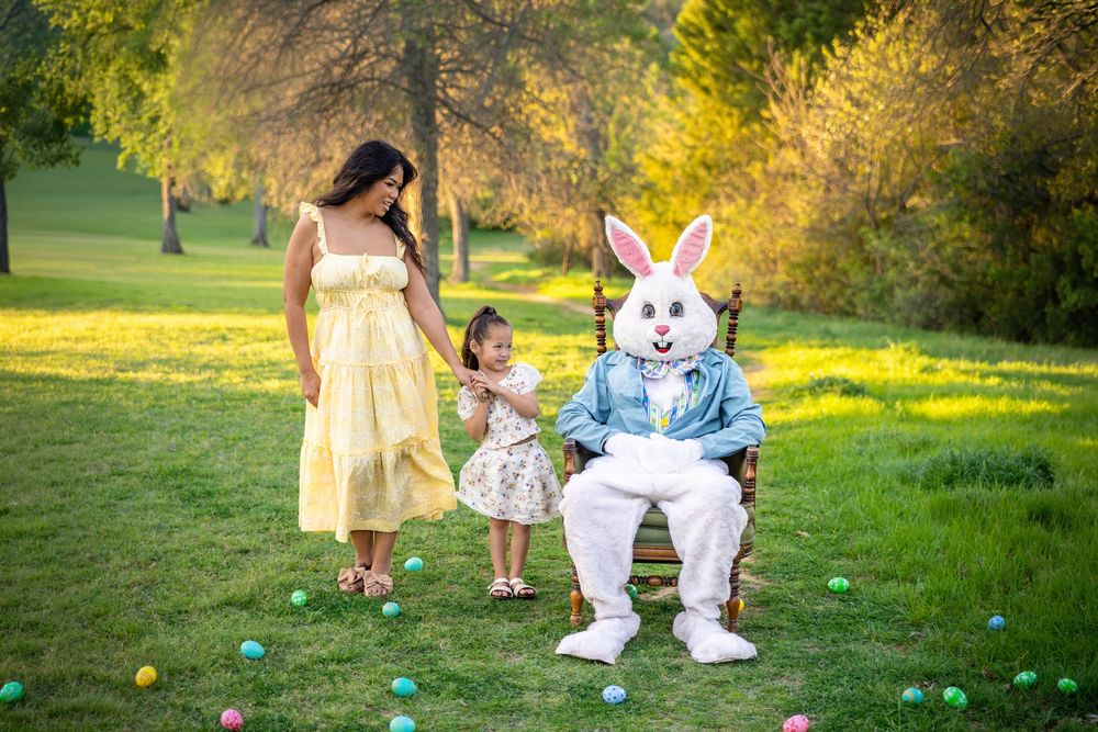 Young girl poses with her Mother in a beautiful green field with the Easter Bunny in an antique chair.