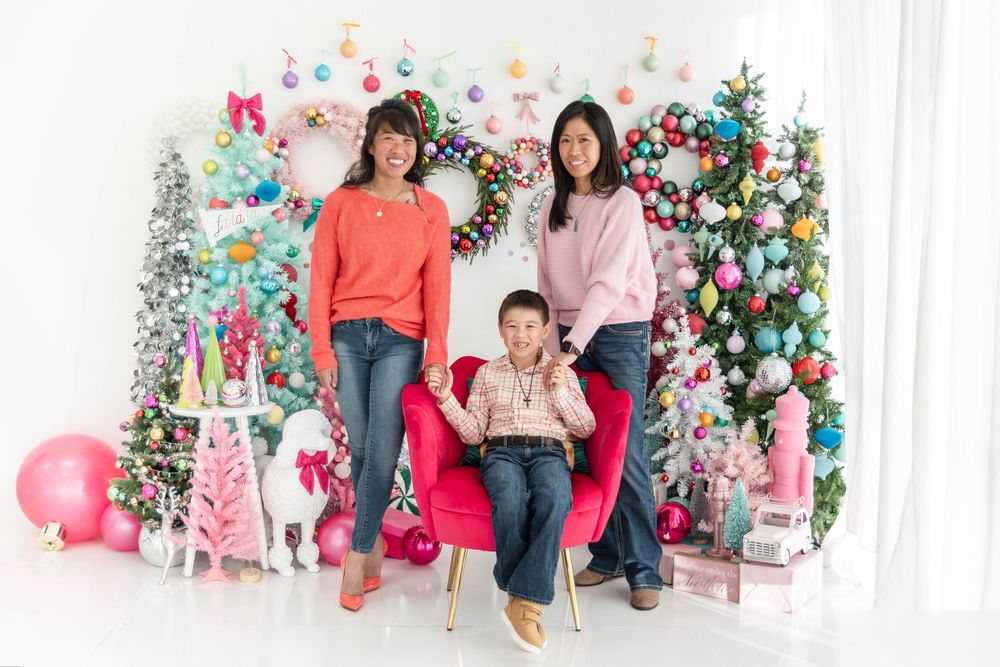 A family poses on a pink and teal Christmas set.