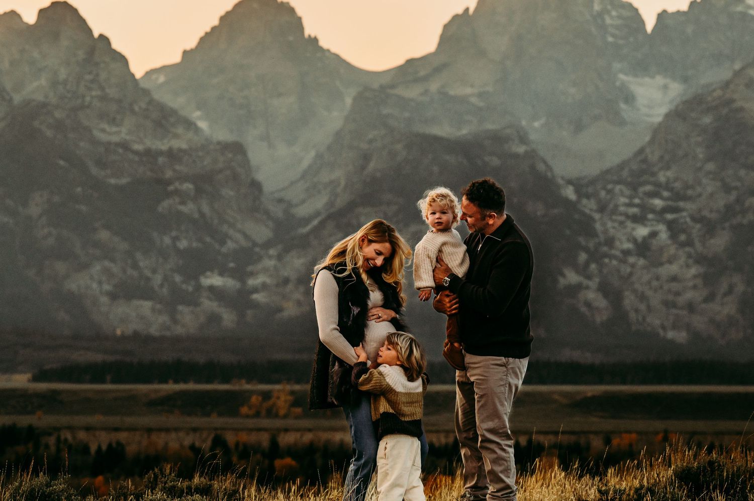 Family portrait with Teton mountain range backdrop at sunset.