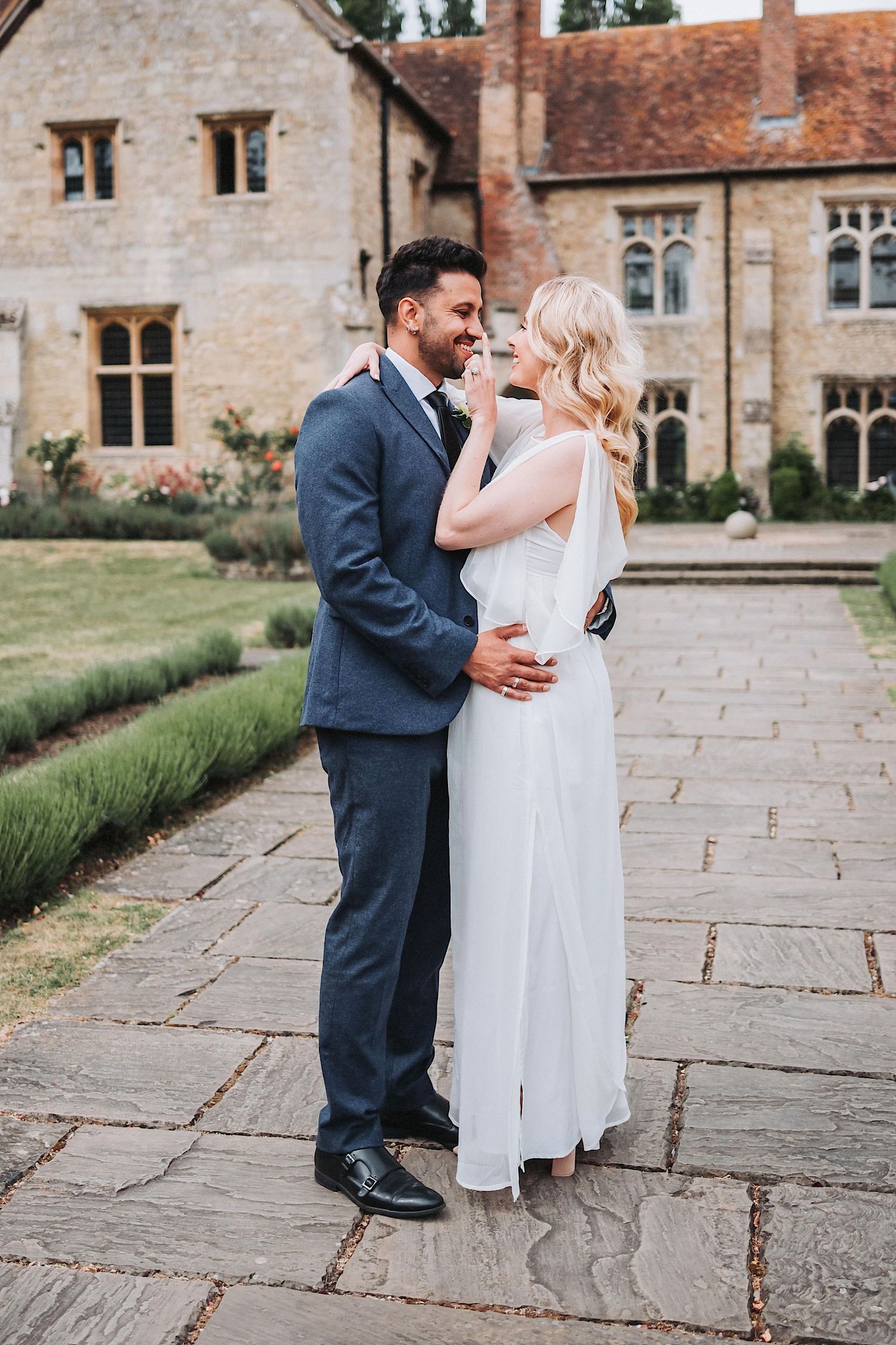 A tender wedding moment captured between couple in navy suit and white gown with long veil.