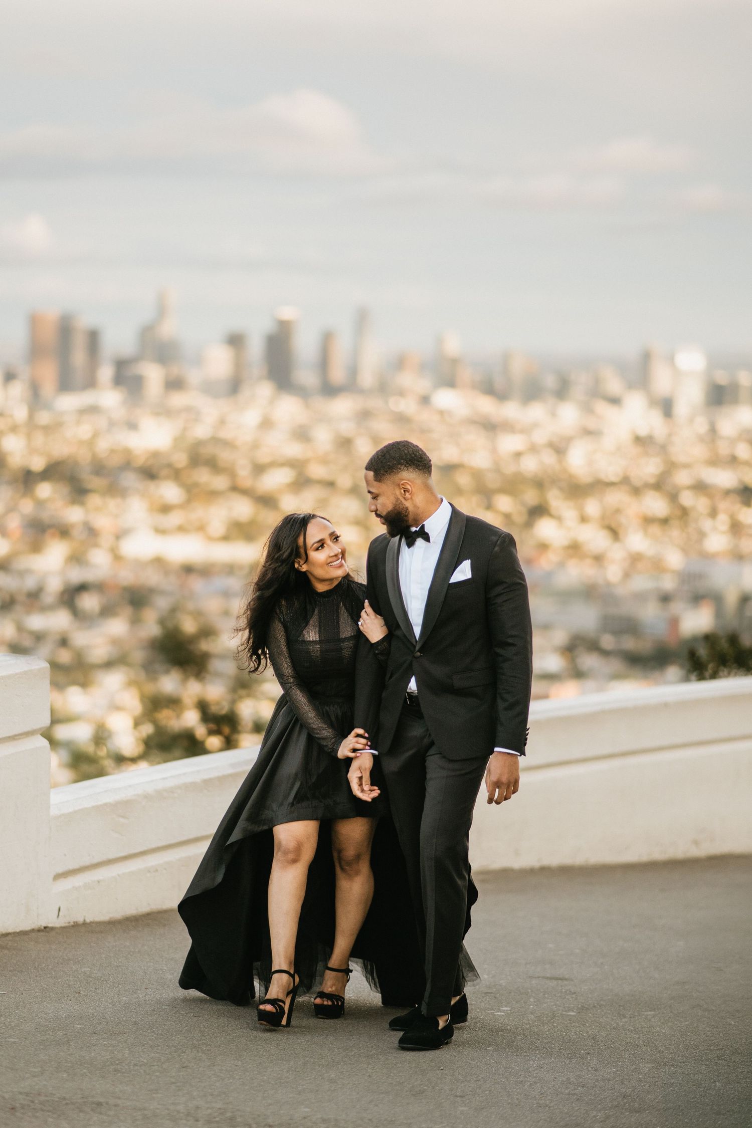 Bride and groom walking together with the Los Angeles skyline behind them during wedding portraits at Griffith Observatory.