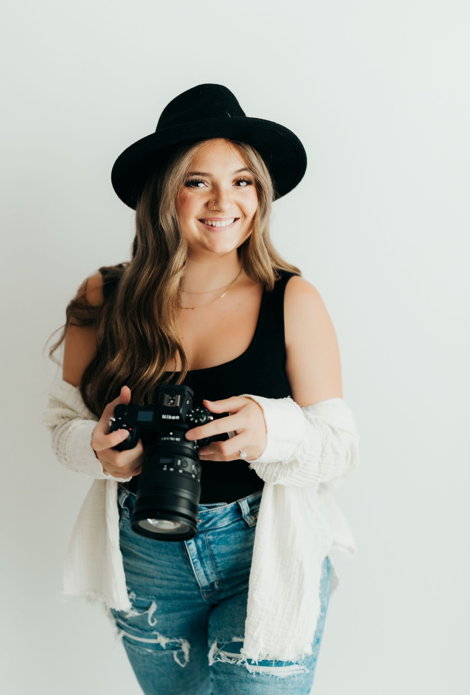 Photographer in chunky knit sweater holding camera against urban backdrop. Clarksville Tn maternity photographer