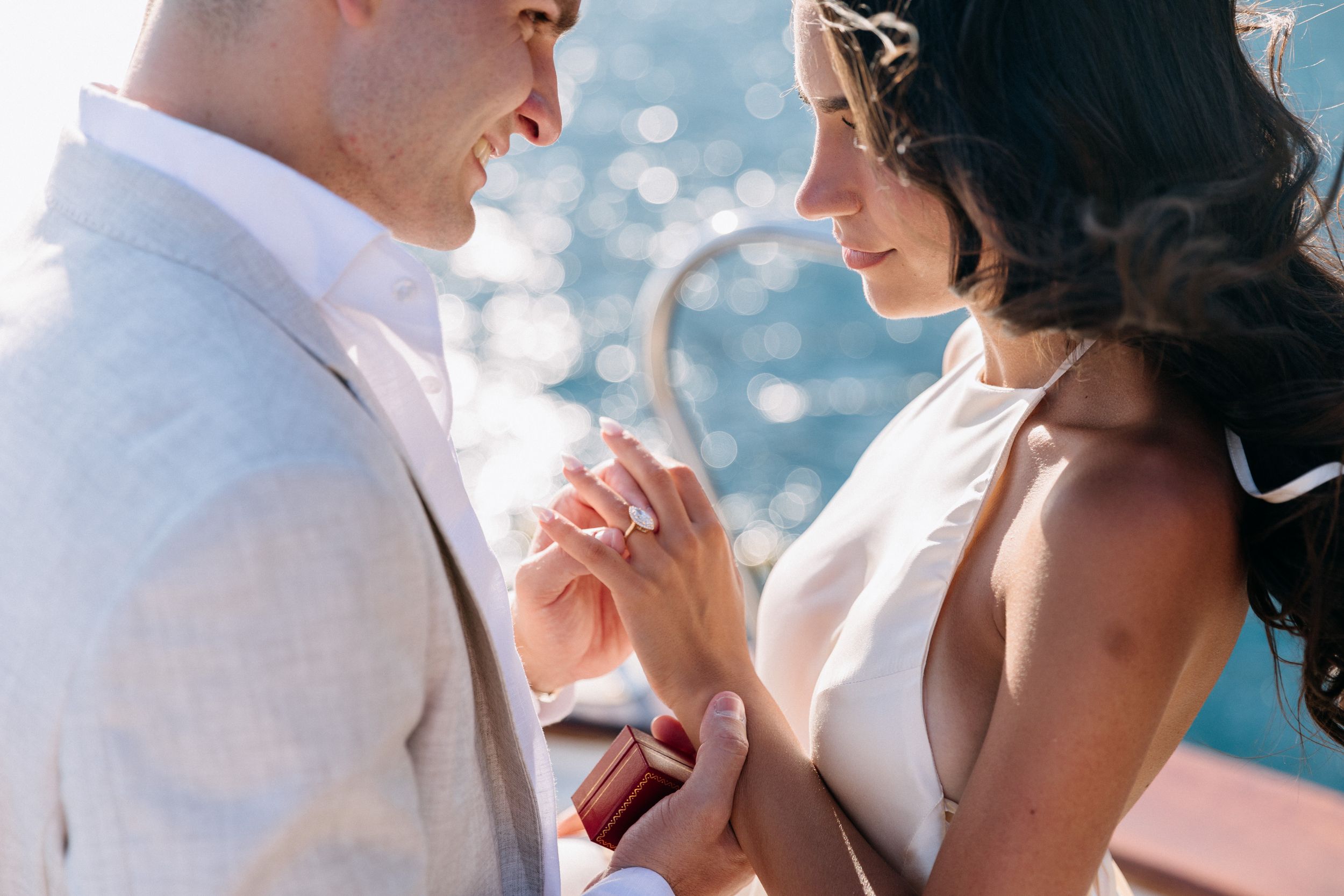 Couple exchanging rings during romantic outdoor wedding ceremony on a sunlit boat deck in Positano