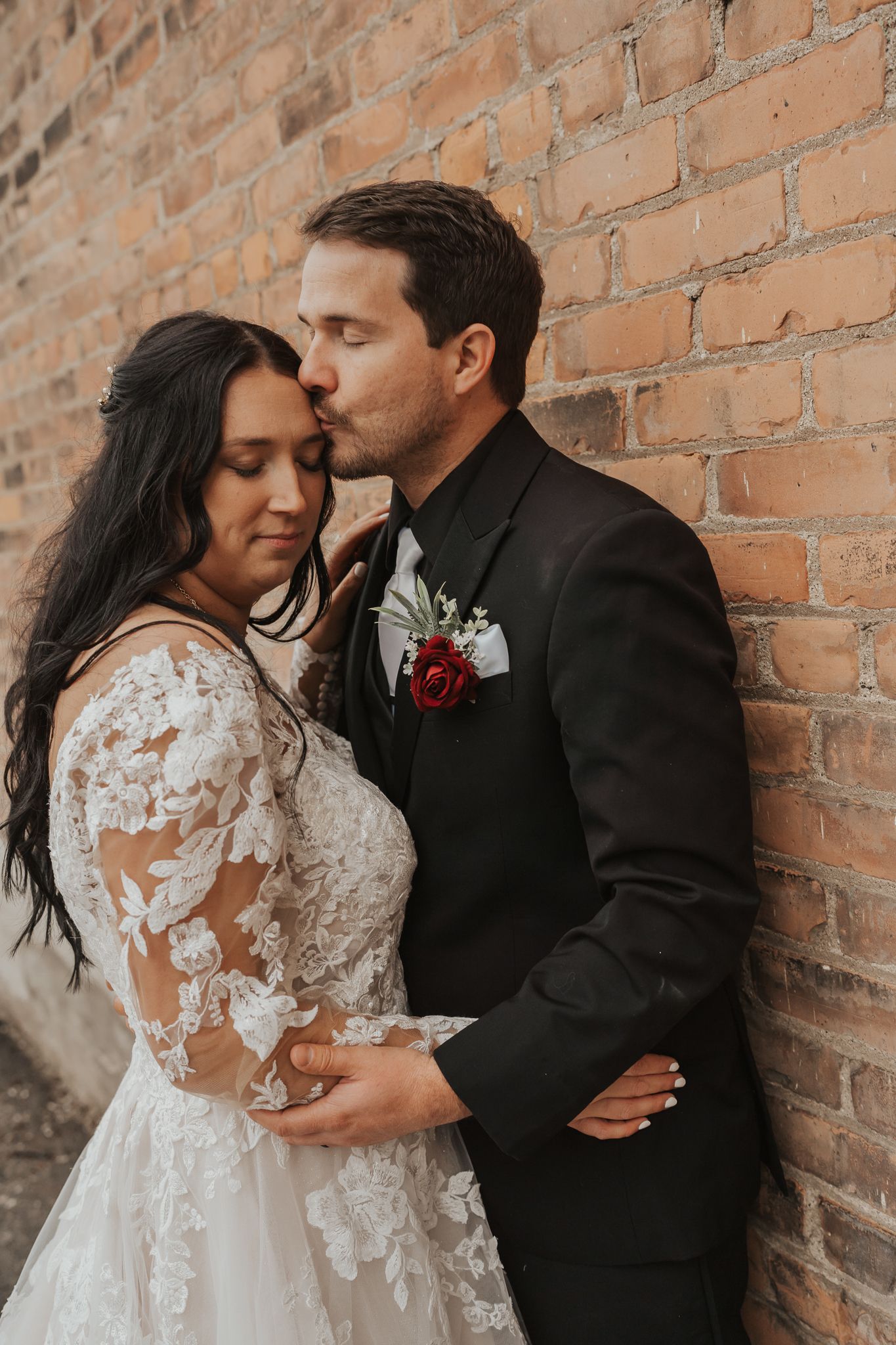 Intimate wedding portraits against textured brick wall background.