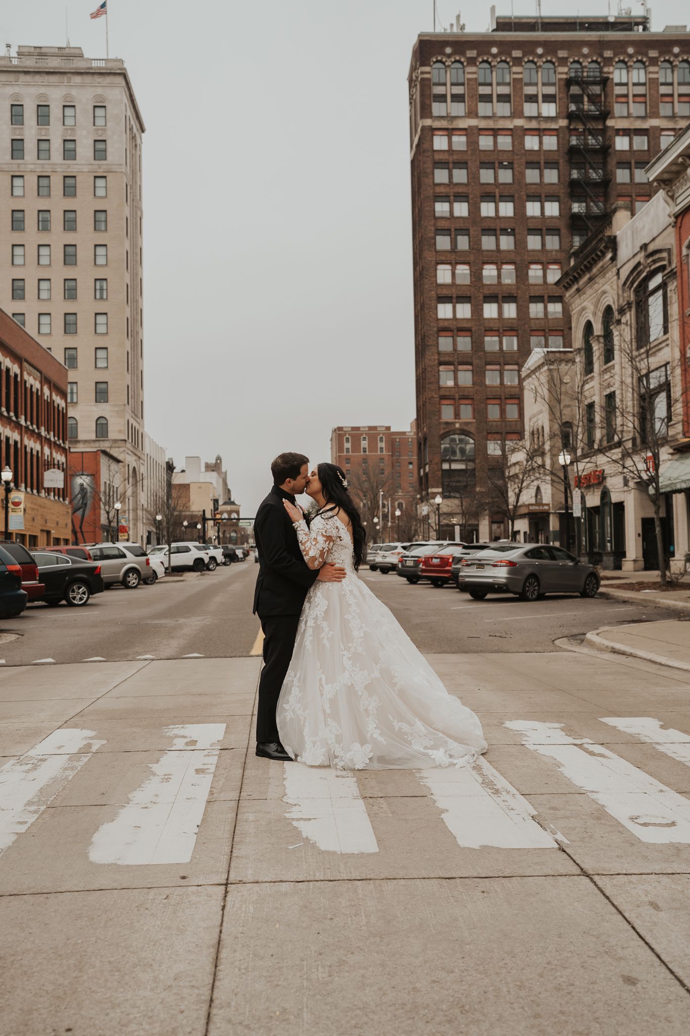 A romantic wedding photo of a couple sharing an intimate moment on a Jackson Michigan street with historic buildings in the background.