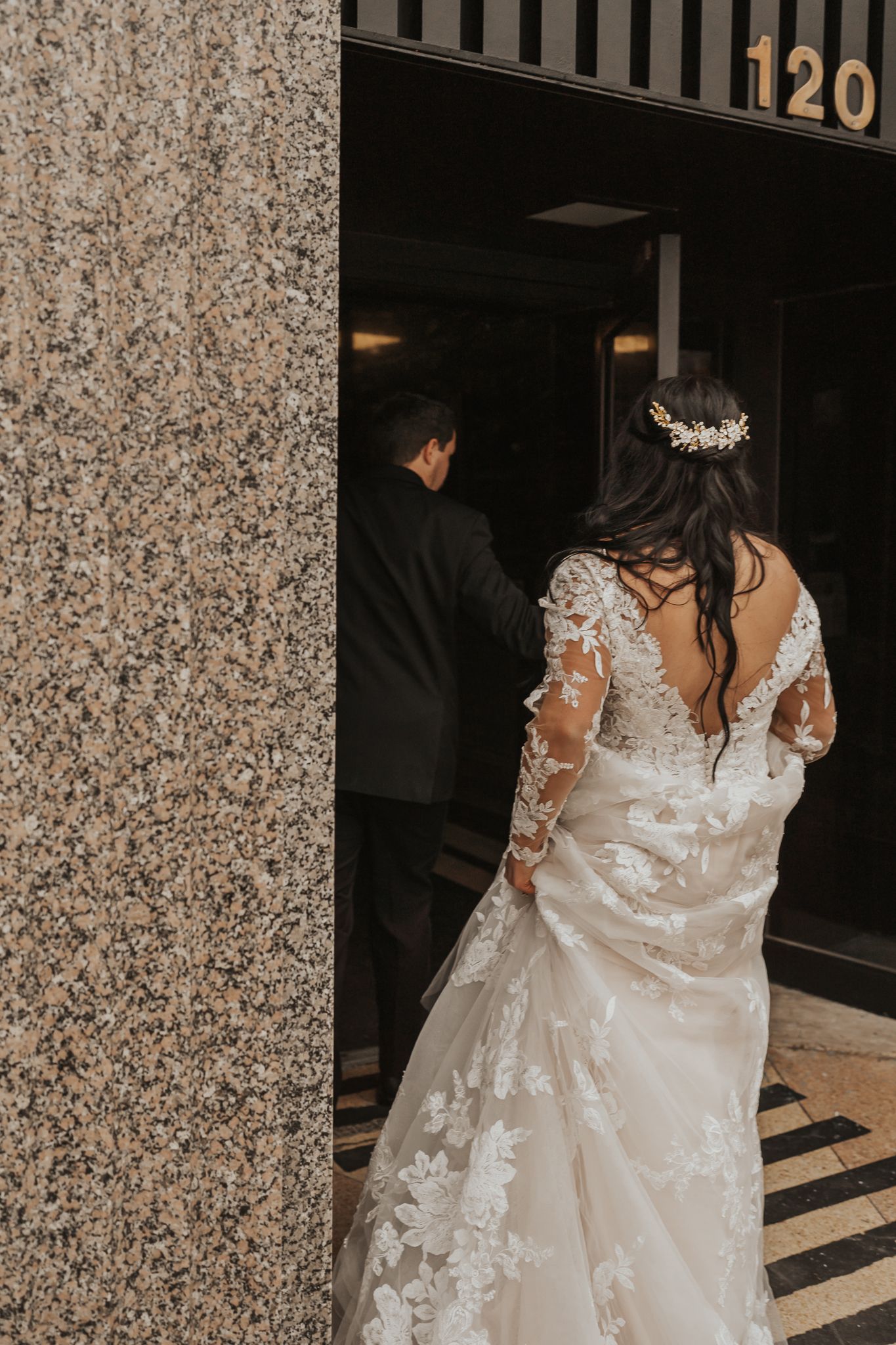 A bride in a lace wedding gown with long sleeves enters a Jackson MI wedding venue.