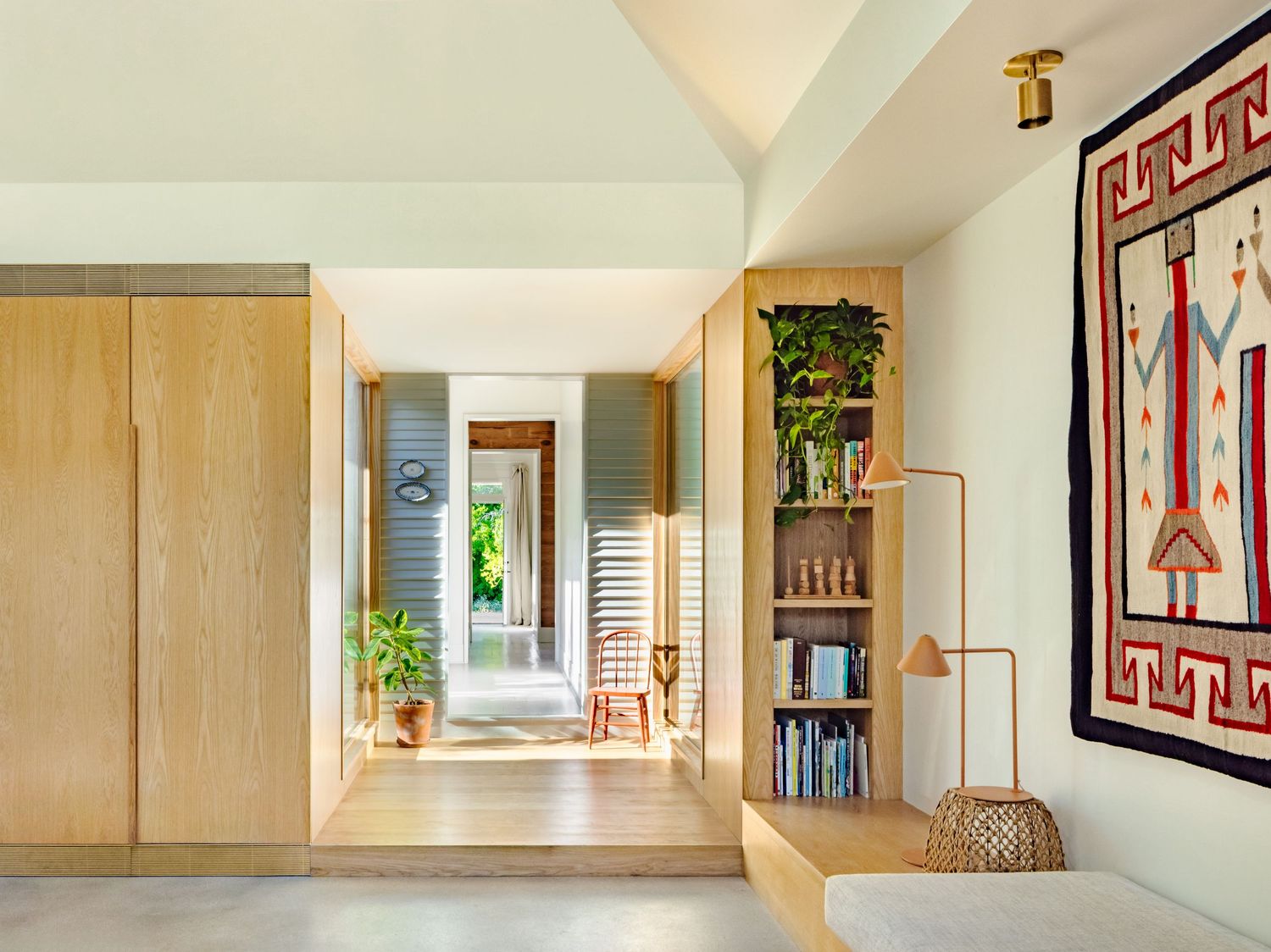 Long hallway with light wood paneling, geometric artwork, and built-in storage solutions.