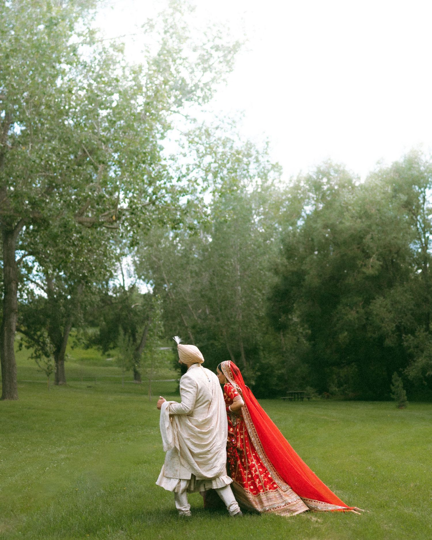 Artistic portrait in red tones showing intricate jewelry details and traditional bridal attire.