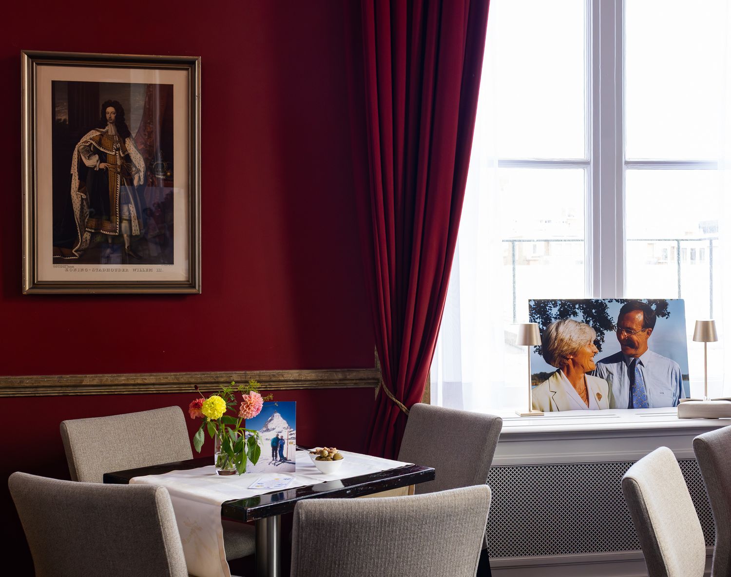 Elegant dining room with burgundy walls, white trim, and framed artwork.