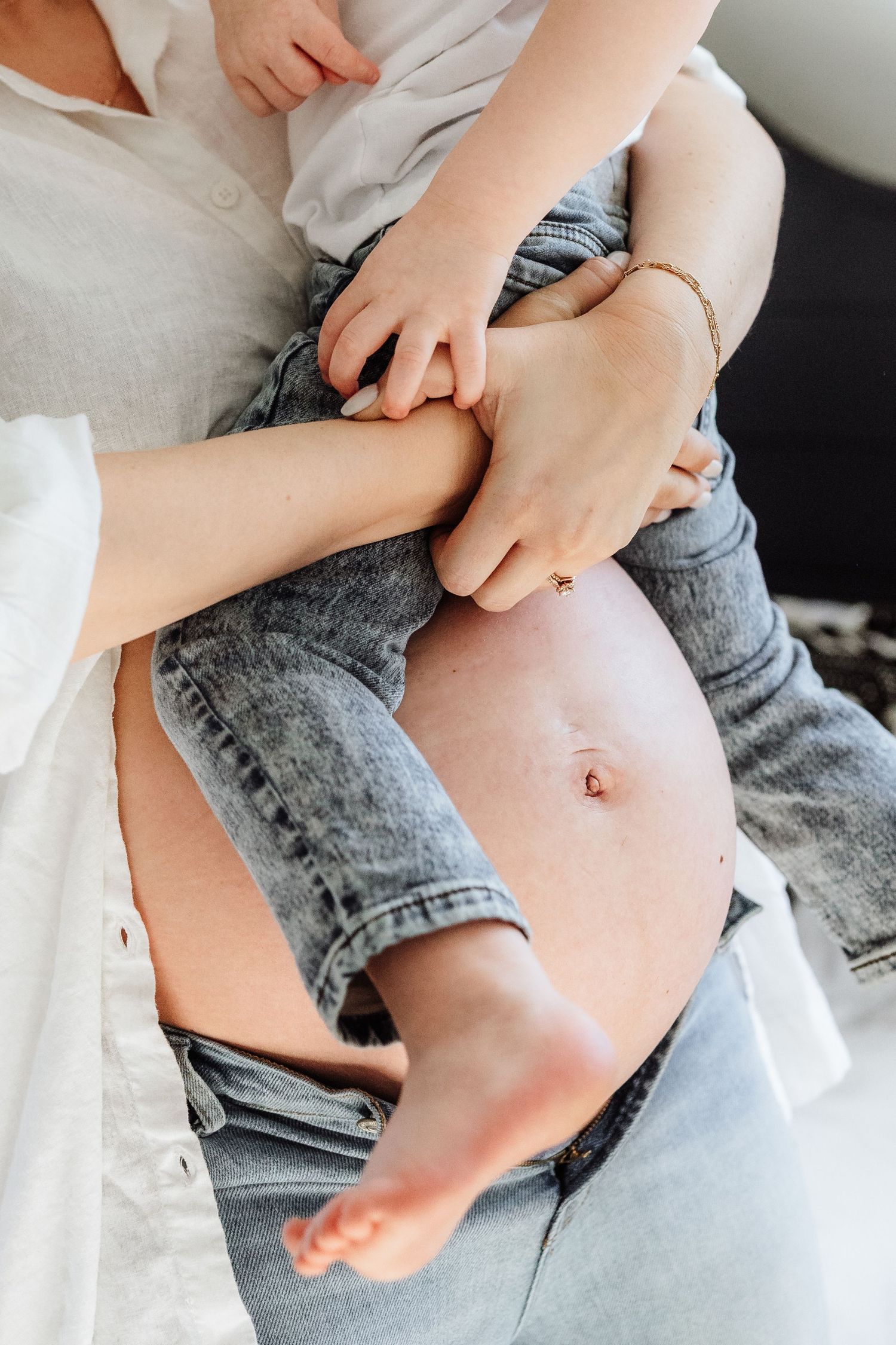 Close-up series showing hands rolling up a denim pant leg to reveal bare skin underneath.