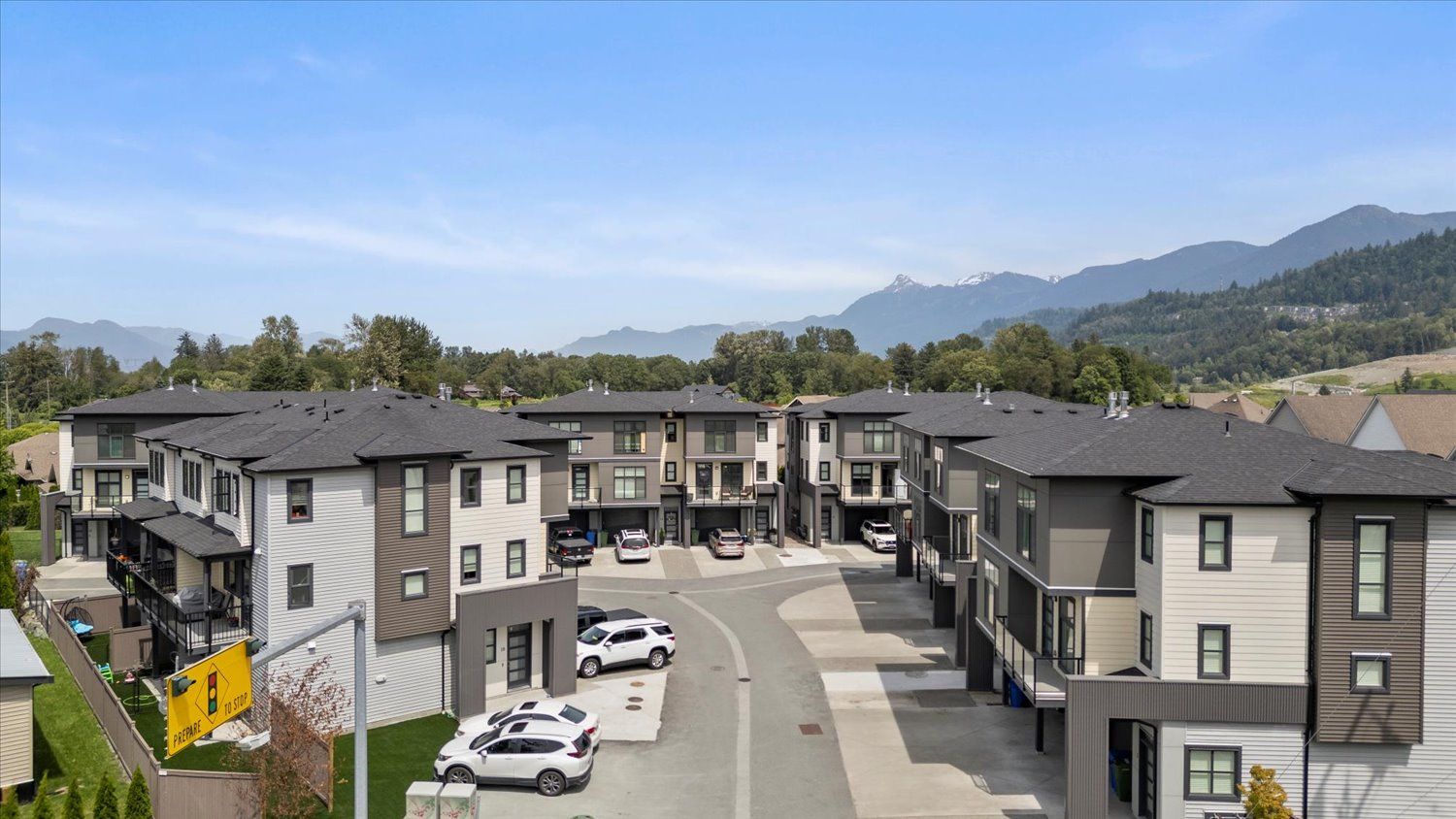 Modern tan townhouse with attached garage and covered entryway in suburban residential neighborhood.