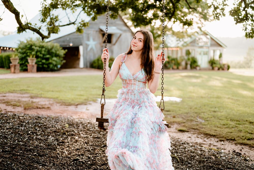 Elegant figure in a floral pastel dress swings outdoors on a summer evening.