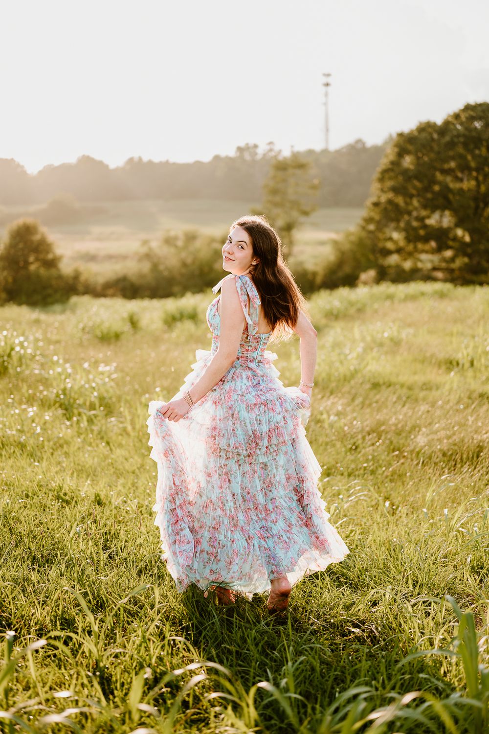Figure in a floral dress twirls gracefully in a sunlit meadow filled with wildflowers.