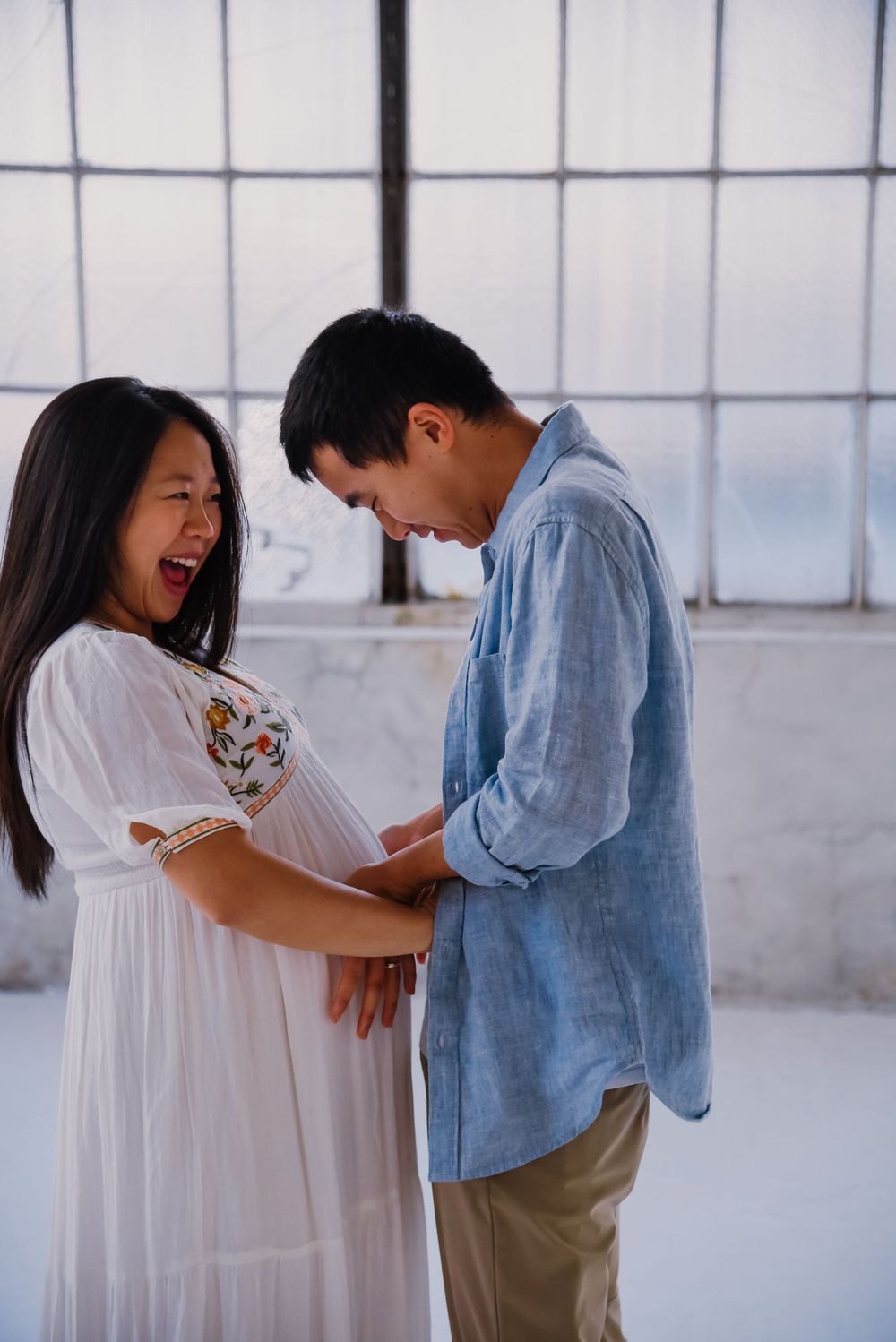 Couple laughs together during maternity photoshoot.