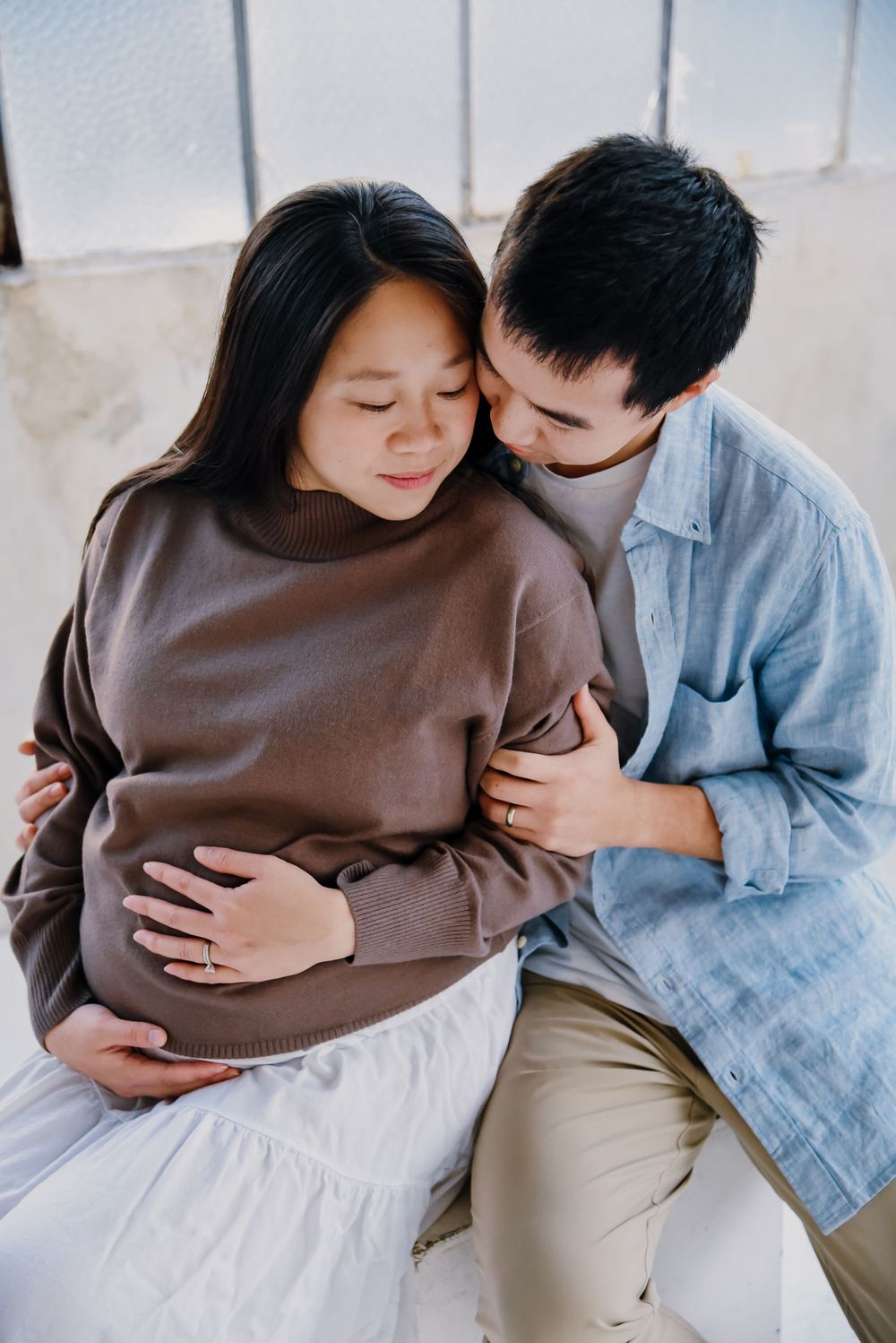 Two people embracing tenderly while wearing brown and denim clothing.