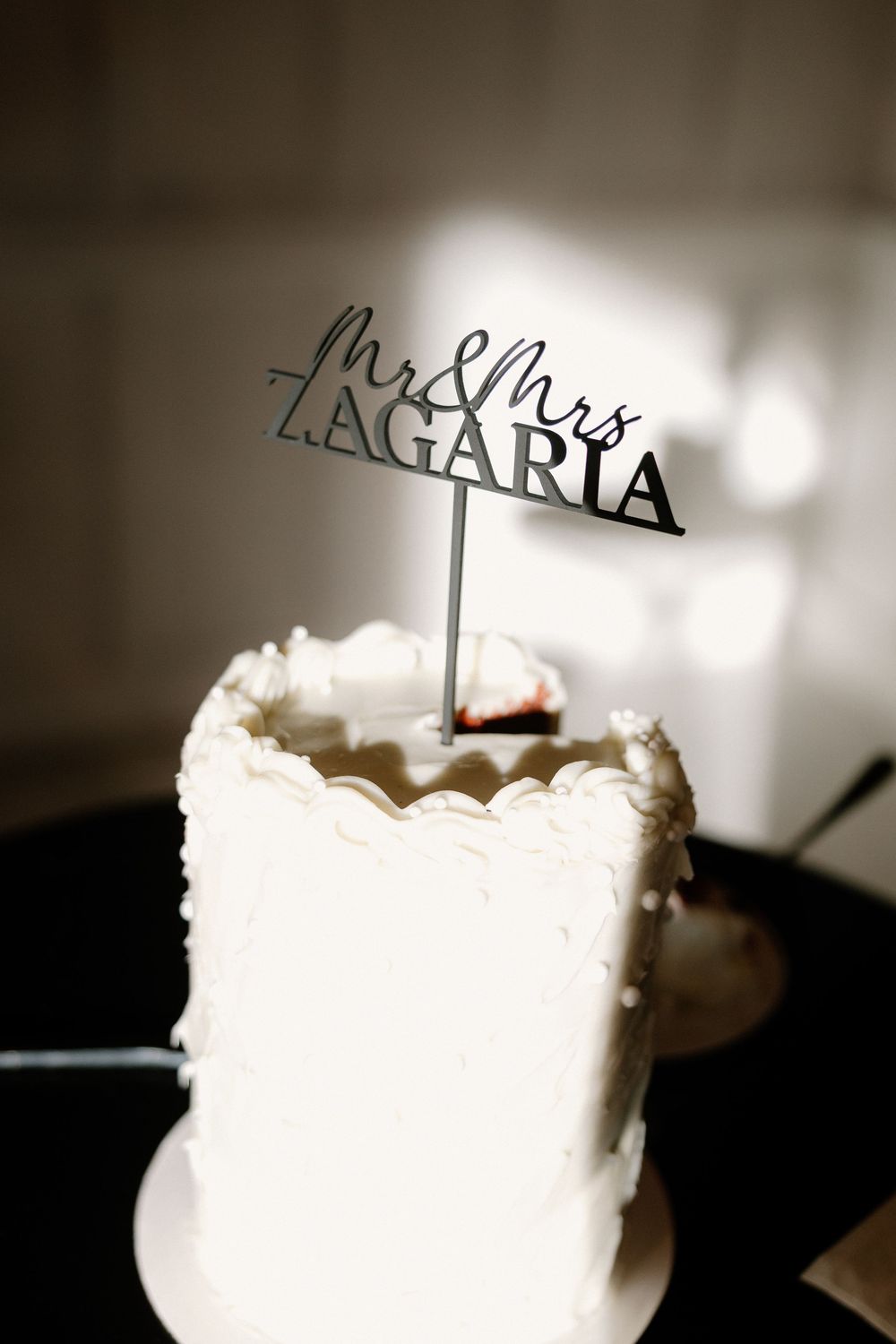Close-up macro sequence of a wedding cake topper decoration with elegant white frosting and metallic text details.