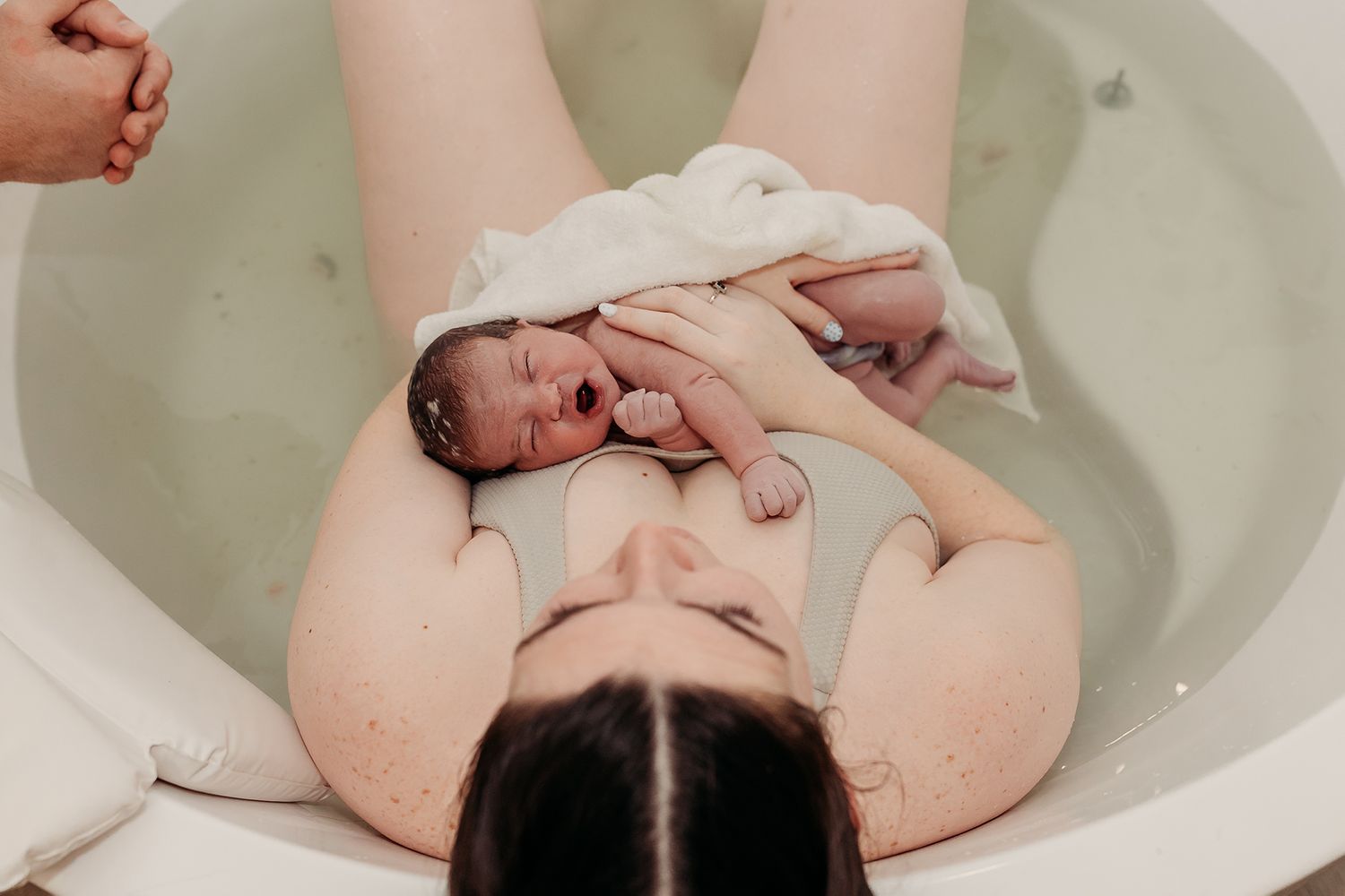 A baby lies in a bathtub during bath time, surrounded by gentle splashes of water.