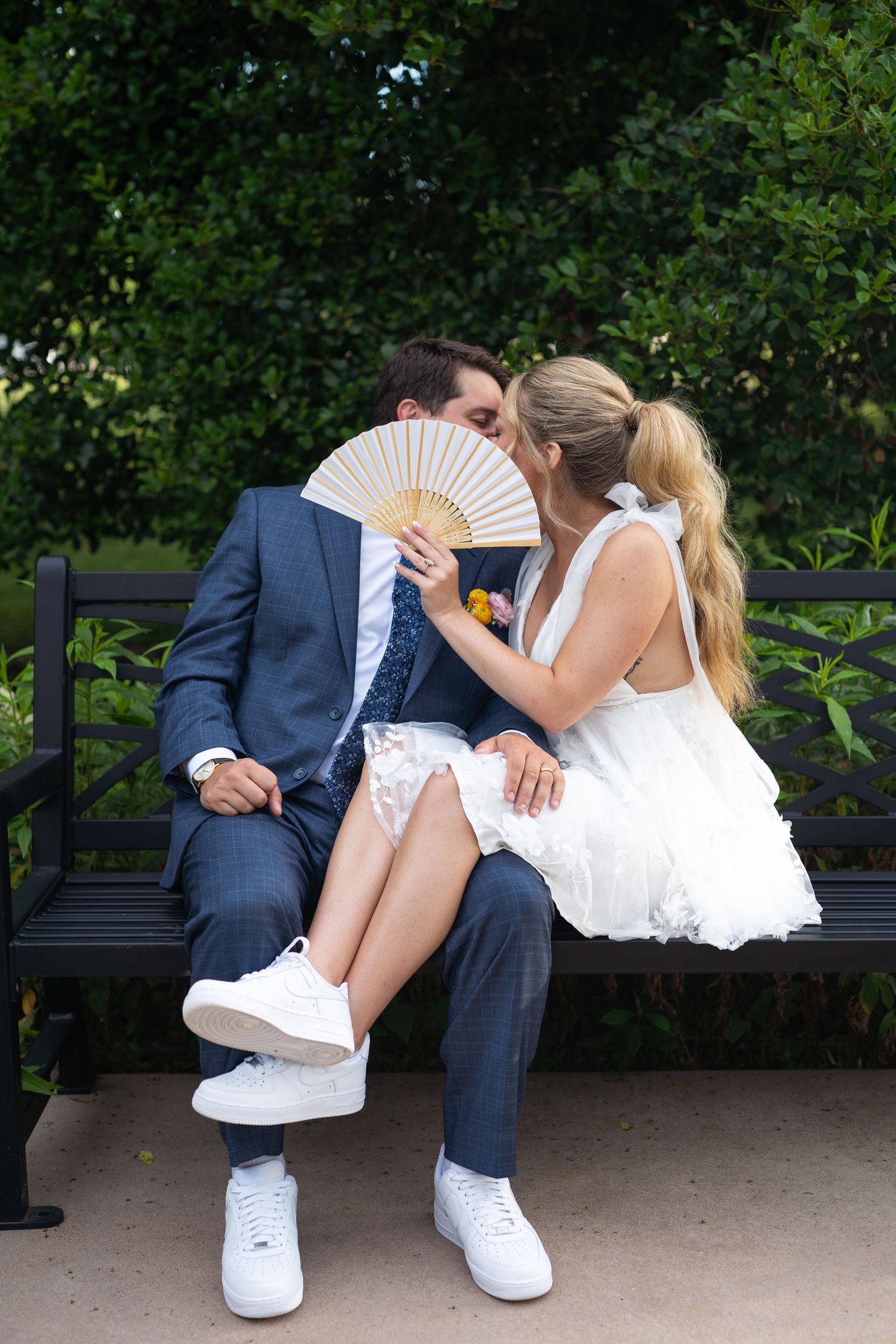 Couple in formal wedding attire sitting on a bench together.