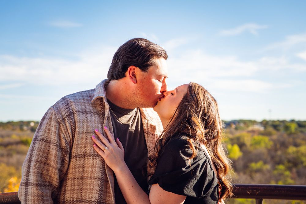 A romantic couple embraces against a blue sky backdrop on a sunny autumn day.