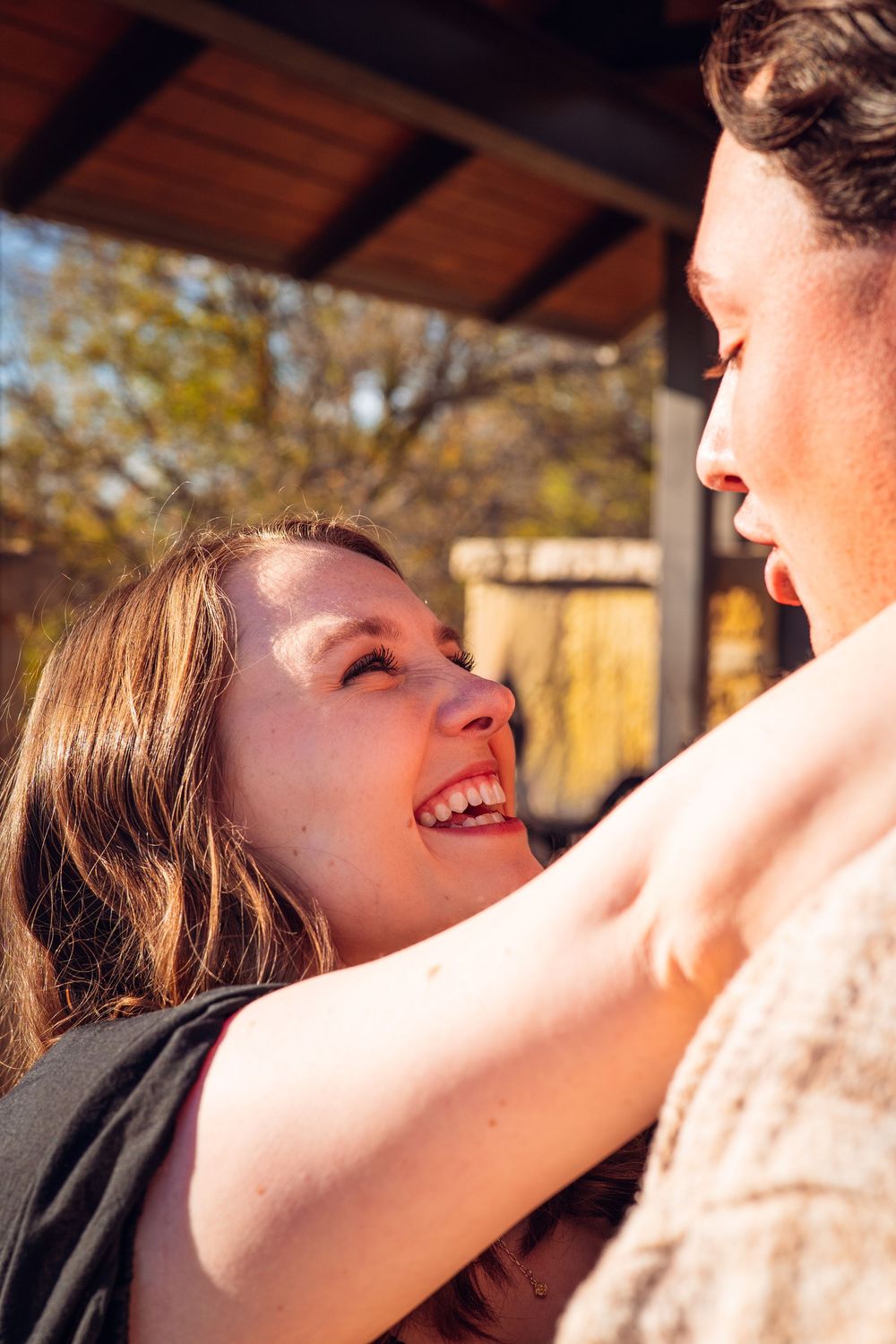 A tender moment captured between a couple under a wooden pergola during golden hour.