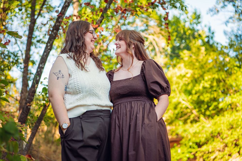 Two people in contrasting outfits share tender moment outdoors.