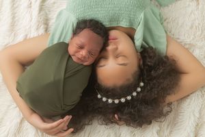 A series of artistic maternity photos showing a pregnant woman in a green dress lying on white fabric.